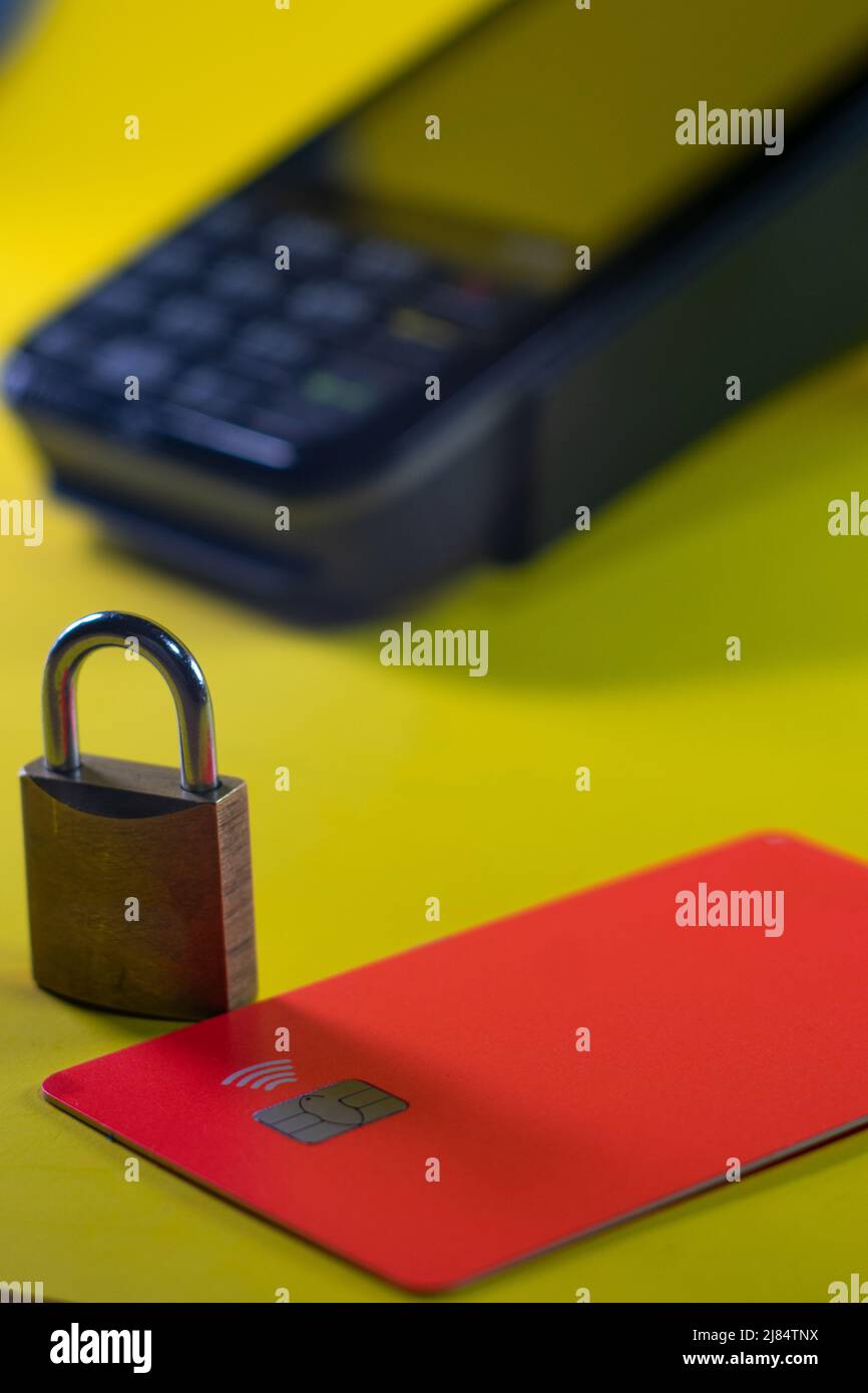 Eine Bankkarte mit einem Vorhängeschloss, das die Sicherheit darstellt, mit einem Kartenterminal im Hintergrund Stockfoto