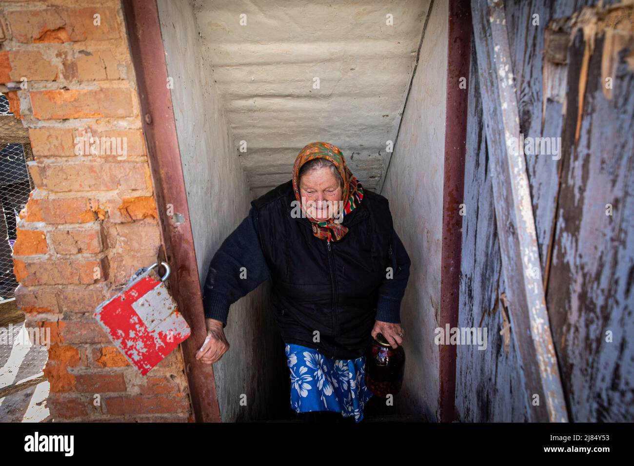 Slatyne, Ukraine. 05.. Mai 2022. Irina, 80 Jahre alt, geht die Treppe des Kellers hinauf, wo sie ohne Strom- und Wasserversorgung lebt. Während Russland seine Truppen wieder ausliefert und die Offensive auf den östlichen Teil der Ukraine konzentriert, sind Charkow und die umliegenden Gebiete in der Ukraine nun ständig von russischen Bombardierungen und Luftangriffen bedroht. Kredit: SOPA Images Limited/Alamy Live Nachrichten Stockfoto