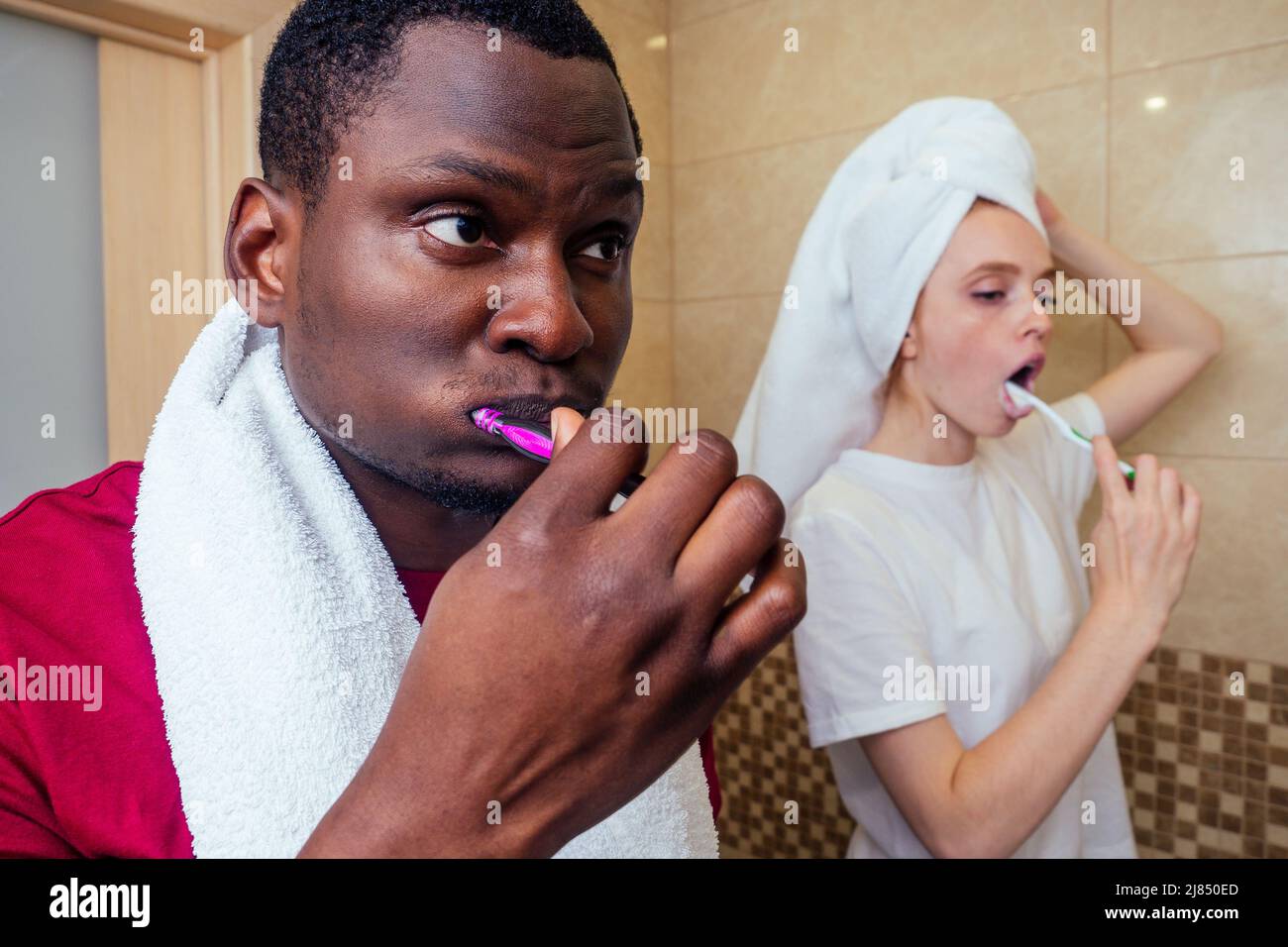 afroamerikanischer Mann und Frau mit nassem Haar auf Handtuch gewickelt nach der Dusche Zahnaufhellung vor dem Arbeitsbeginn Stockfoto
