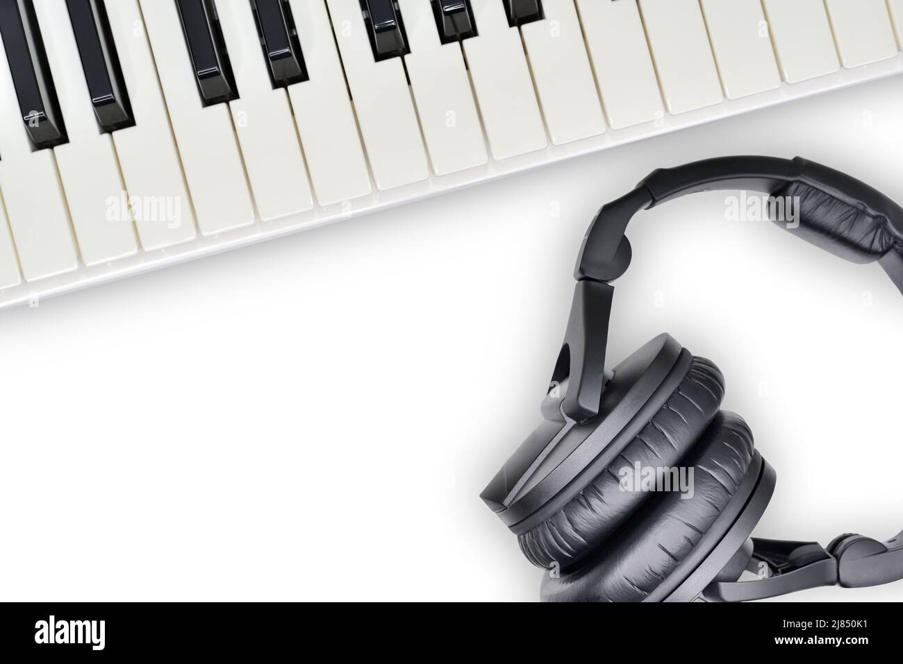 Draufsicht auf Kopfhörer und Synthesizer-Tastatur auf weißem Hintergrund. Professionelle Studio-Ausrüstung für Aufnahme und Wiedergabe von Musik. Stockfoto
