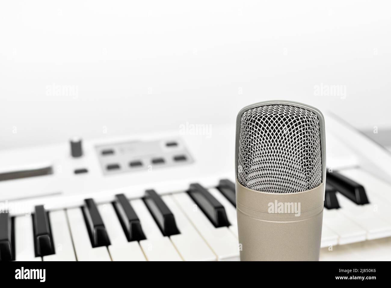 Professionelles Studiomikrofon für sprach- und Musikaufnahmen vor unscharfem Synthesizer-Keyboard-Hintergrund mit Kopierraum. Stockfoto