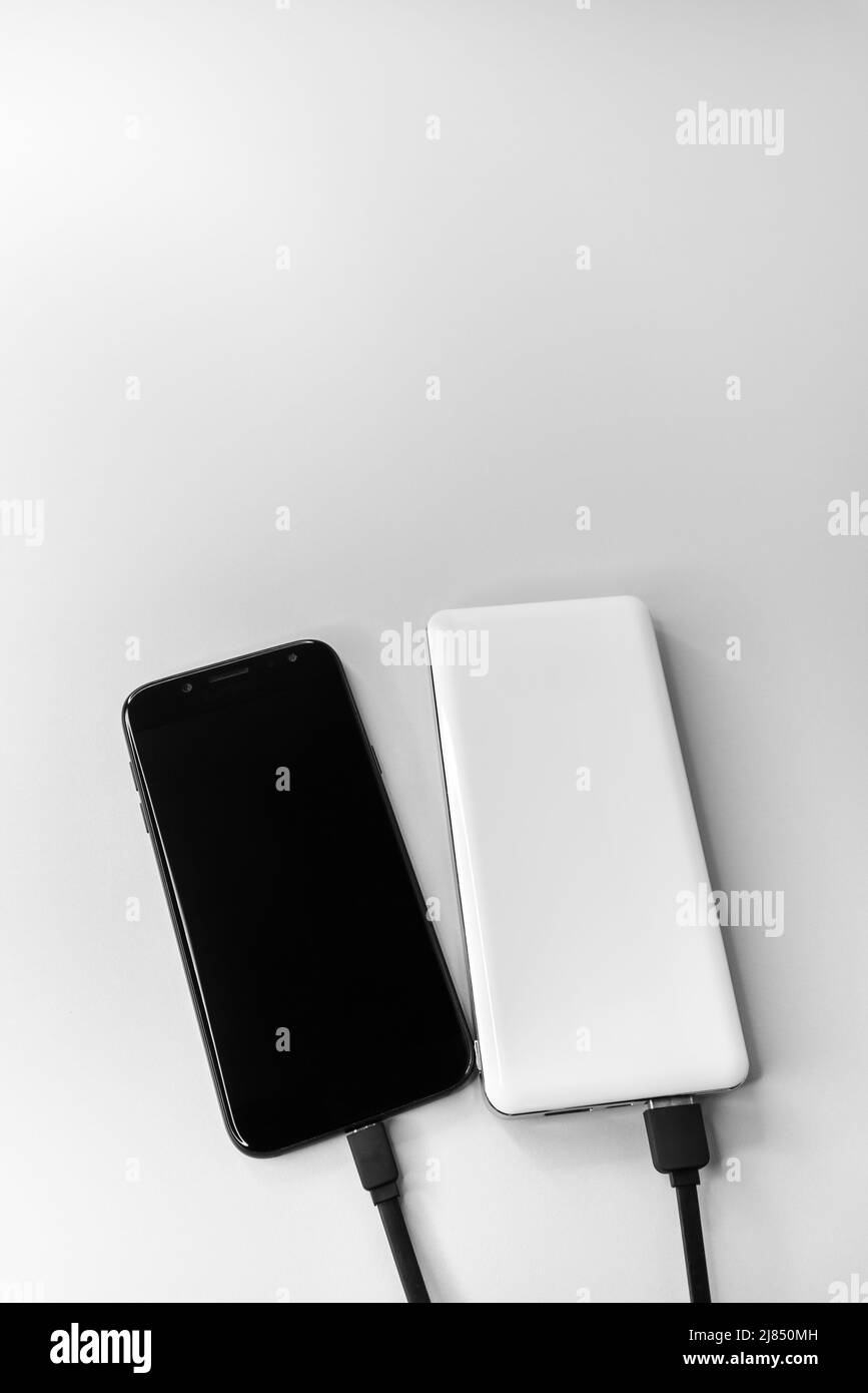 Smartphone und Powerbank während des kabelgebundenen Ladevorgangs. Stockfoto