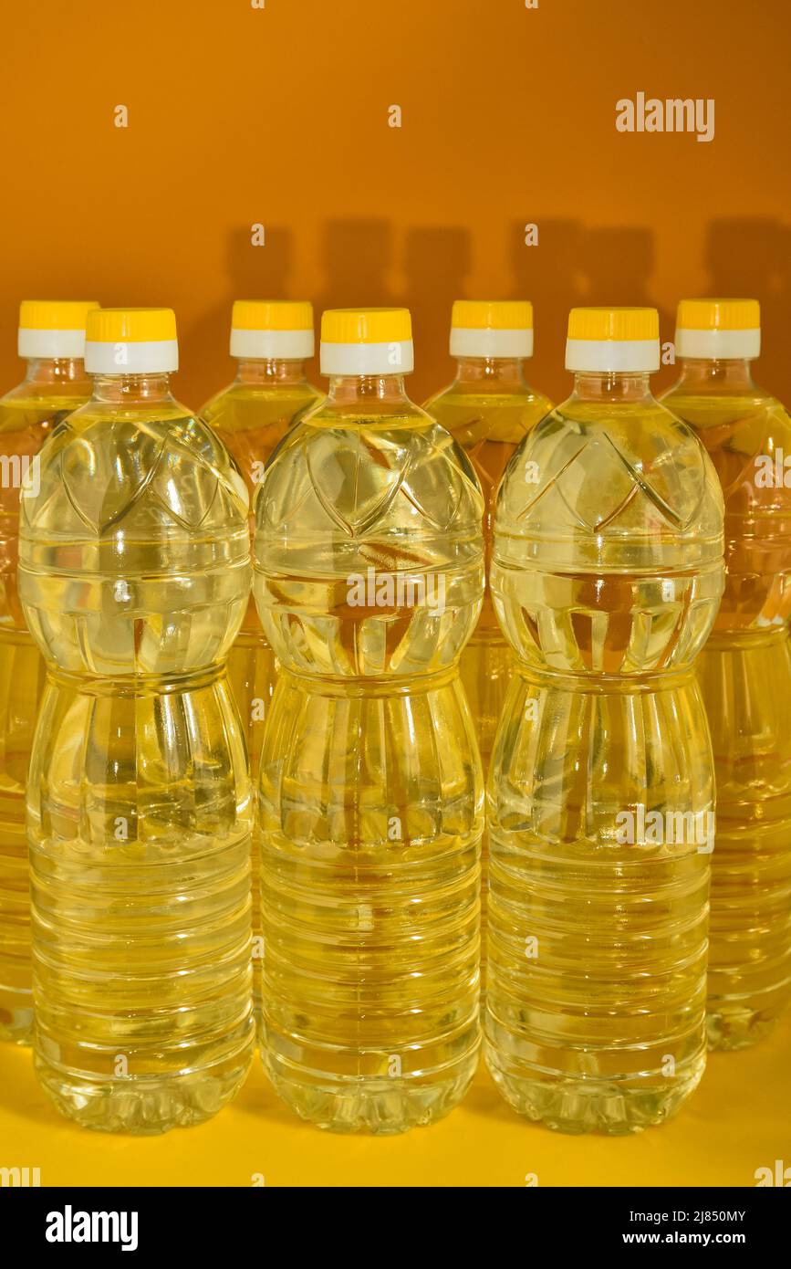 Plastikflaschen mit natürlichem, raffiniertem Sonnenblumengemüseöl auf orangefarbenem Hintergrund Stockfoto
