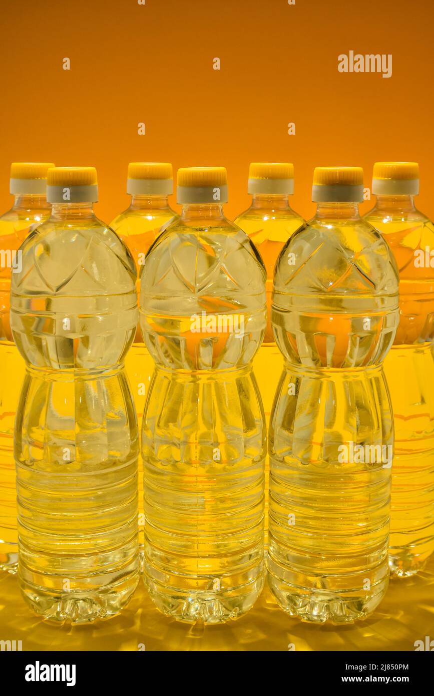 Plastikflaschen mit natürlichem raffiniertem Sonnenblumenöl auf orangefarbenem Hintergrund Stockfoto