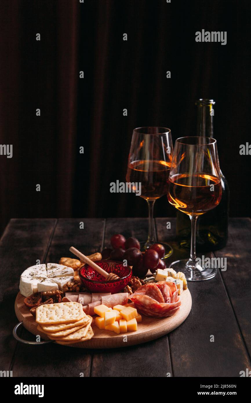 Wurst und Käse, geschnitten mit Obst, Keksen und Sauce, mit zwei Gläsern weißem Portwein und einer Flasche. Aufschnitt und Käseplatte Stockfoto