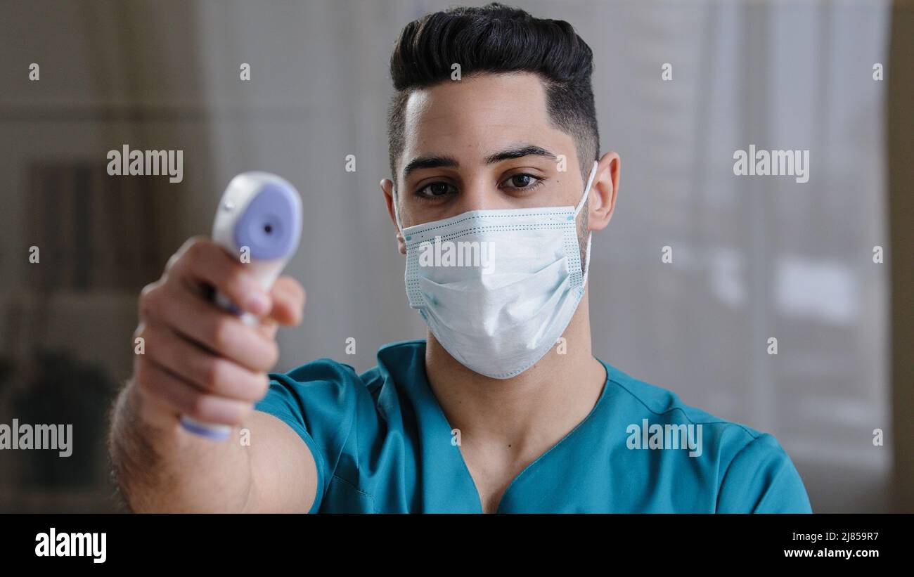 Arabischer männlicher Arzt Arzt Chirurg Mann in Schutzmaske, der während des Covid-19 Temperatur mit berührungslosen Infrarot-Digitalthermometern aufnahm Stockfoto