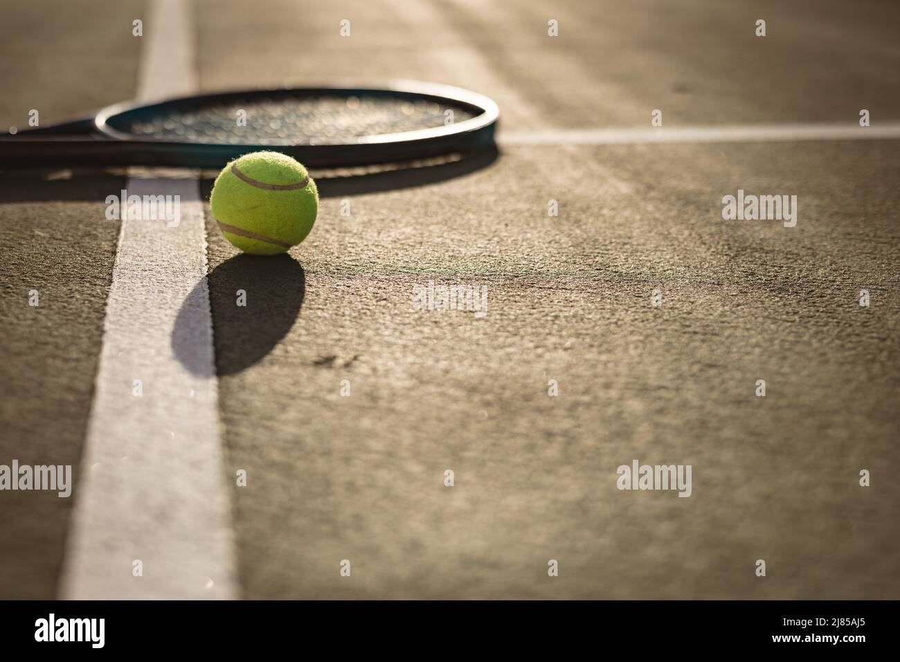 Oberfläche des Tennisballs und Schlägers auf weißen Linien auf dem Tennisplatz bei Sonnenuntergang, Platz kopieren Stockfoto