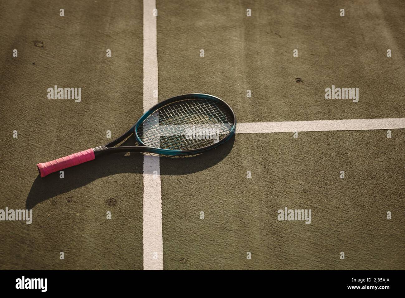 Hohe Winkelansicht des Tennisschlägers auf weißen Linien auf dem Tennisplatz bei Sonnenuntergang, Kopierfläche Stockfoto