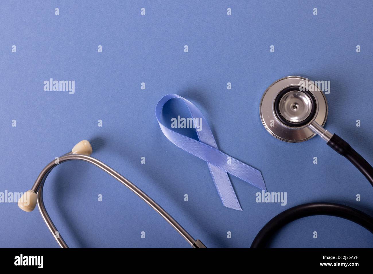 Direkt über Aufnahme von blauem Magenkrebs-Bewusstseinsband und Stethoskop auf blauem Hintergrund Stockfoto