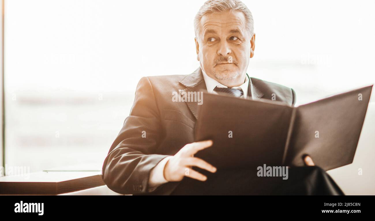 Erfolgreicher Geschäftsmann studiert Arbeitspapiere, die auf dem Sofler sitzen Stockfoto