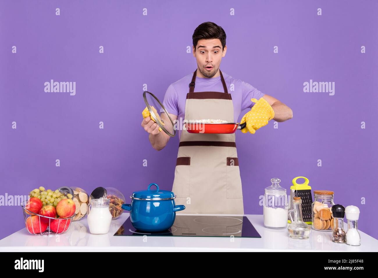 Foto von funky beeindruckt Freund gekleidet Koch Outfit suchen verbrannten Abendessen isoliert lila Farbe Hintergrund Stockfoto