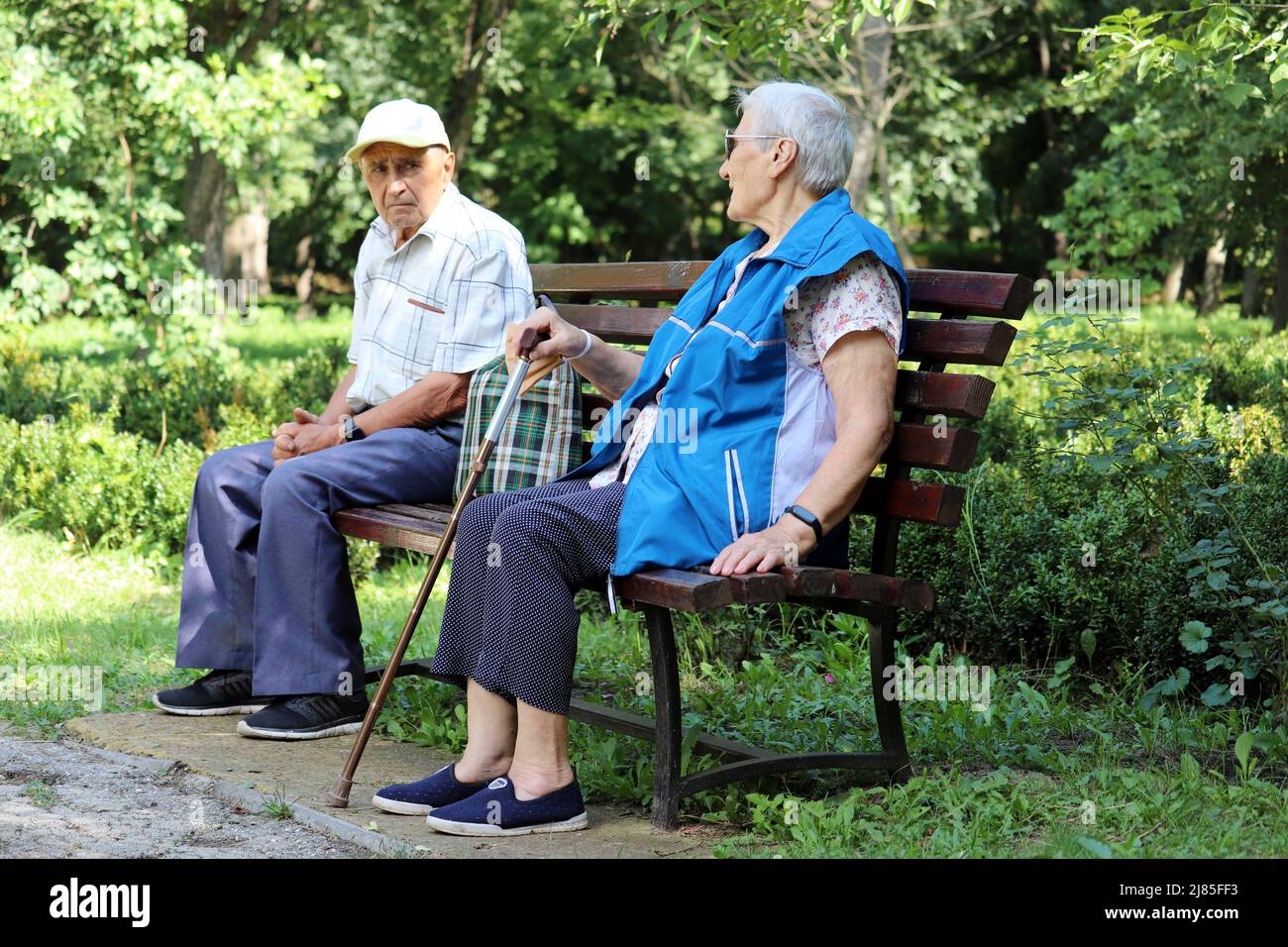 Ein älteres Paar sitzt auf einer Bank im Sommerpark. Alter Mann und Frau zusammen, Freizeit in der Natur, Leben im Ruhestand Stockfoto