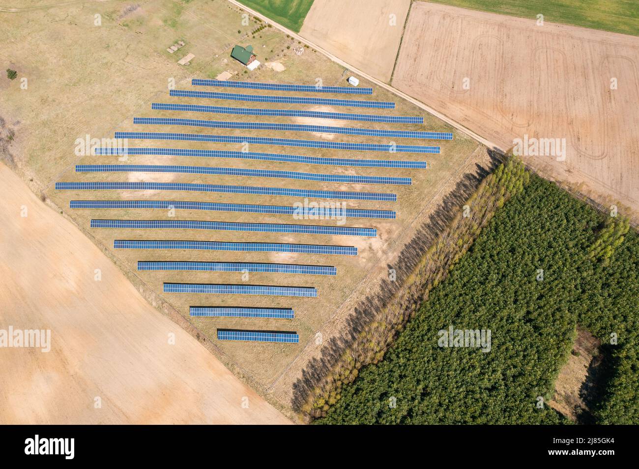 Solarfarm Luftaufnahme, Reihen von PV-Modulen bei einem kleinen Haus Stockfoto