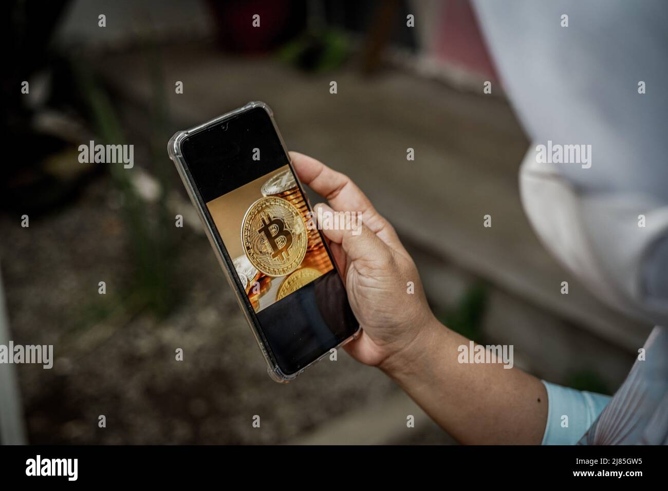Makassar, Süd-Sulawesi, Indonesien. 13.. Mai 2022. Eine Frau hält ein Mobiltelefon, das ein Bitcoin-Bild auf dem Bildschirm zeigt. In den letzten Tagen ist der Preis für Bitcoin drastisch gesunken. (Bild: © Herwin Bahar/ZUMA Press Wire) Stockfoto