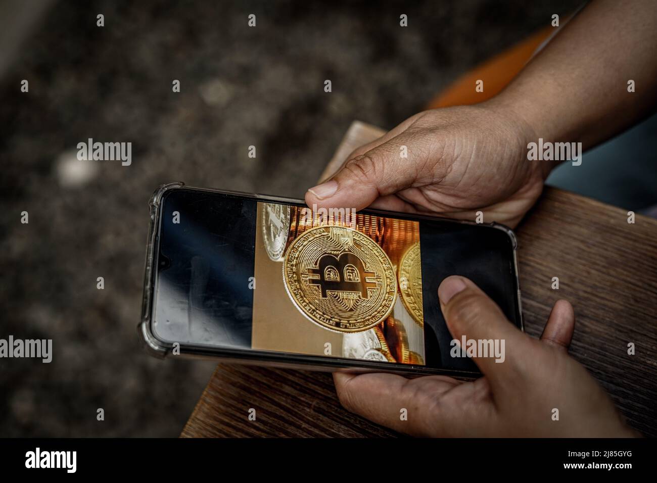 Makassar, Süd-Sulawesi, Indonesien. 13.. Mai 2022. Eine Frau hält ein Mobiltelefon, das ein Bitcoin-Bild auf dem Bildschirm zeigt. In den letzten Tagen ist der Preis für Bitcoin drastisch gesunken. (Bild: © Herwin Bahar/ZUMA Press Wire) Stockfoto