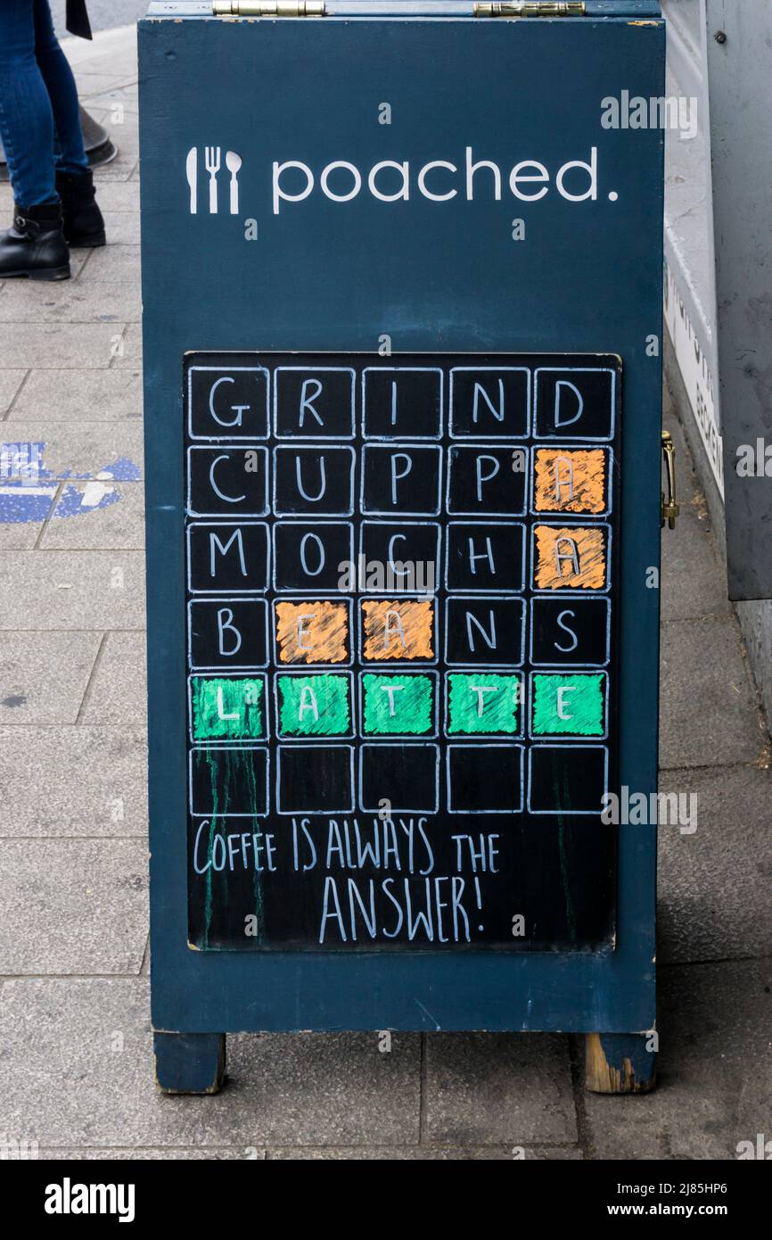 In einem Werbespot in einer Kaffeebar wird die Besessenheit der Menschen mit dem Wortspiel „Wordle“ wiedergegeben. Stockfoto