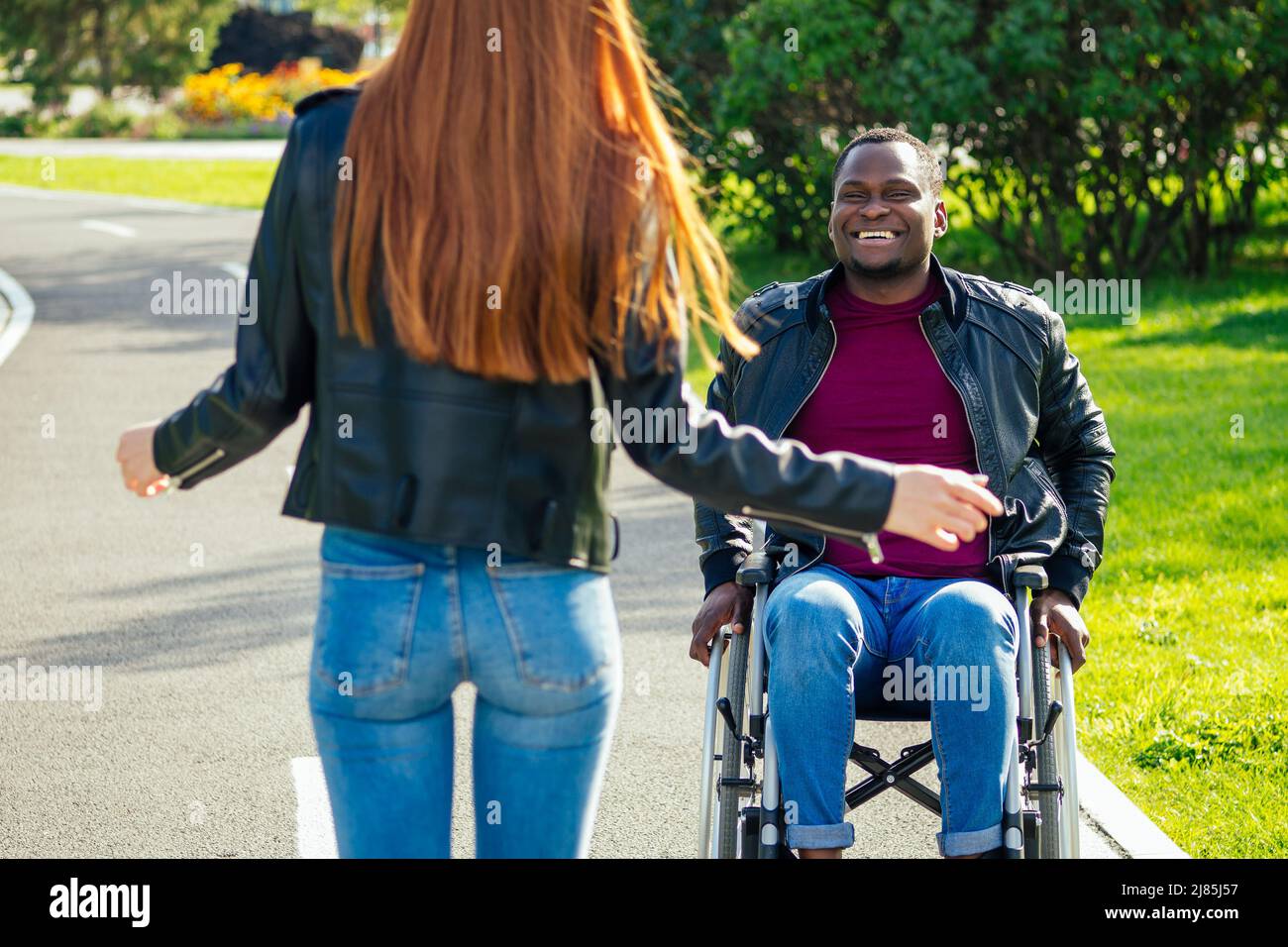afro-amerikanischer Mann auf Rollstuhl sitzend, seine rothaarige Ingwer-Freundin Rolling Kinderwagen im Herbst Park. Mit romantischen Datum Stockfoto