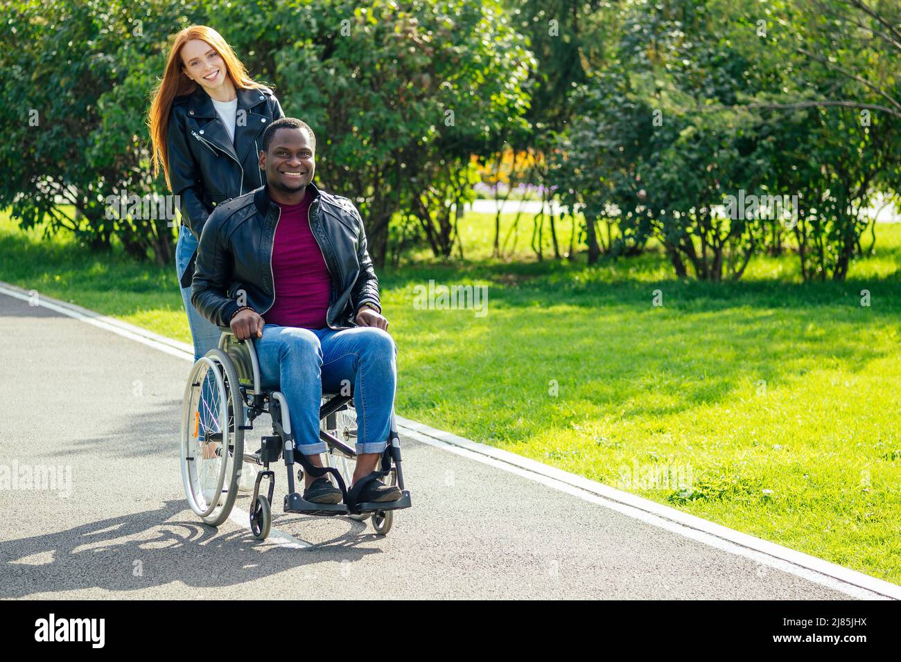 afro-amerikanischer Mann auf Rollstuhl sitzend, seine rothaarige Ingwer-Freundin Rolling Kinderwagen im Herbst Park. Mit romantischen Datum Stockfoto