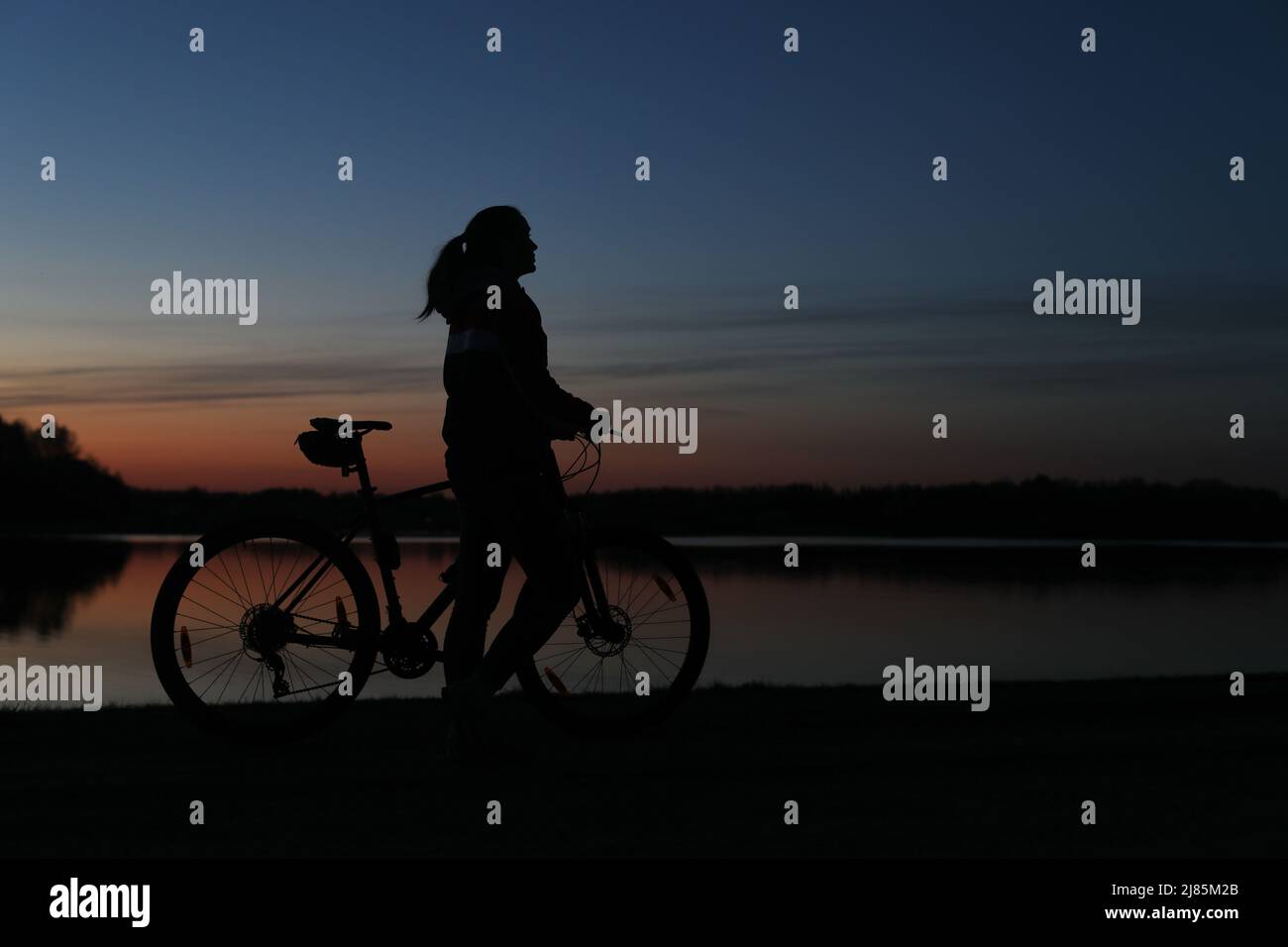 Silhouette der Frau mit Mountainbike auf bunten blauen Himmel Sonnenuntergang Hintergrund. Aktiver Lebensstil im Freien Stockfoto
