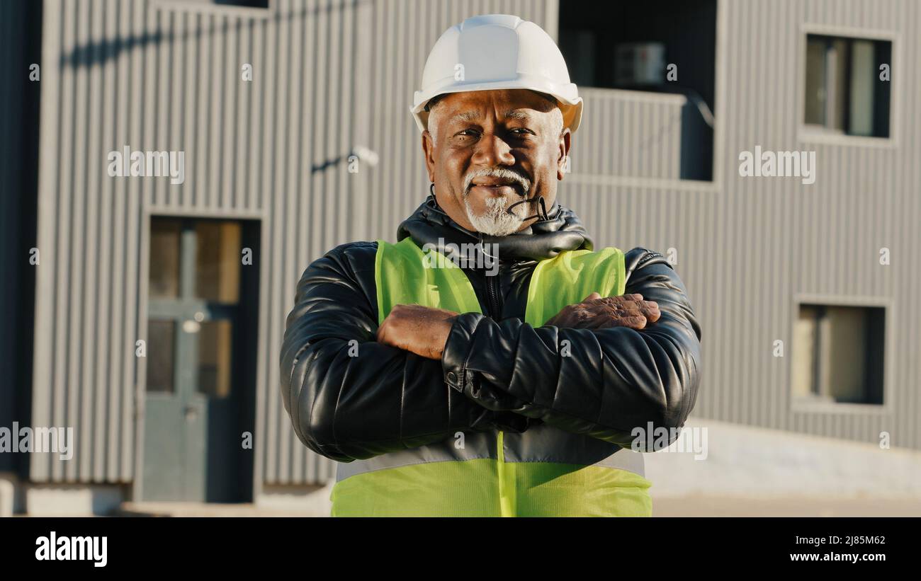 Nahaufnahme älterer afroamerikanischer Bauarbeiter, der in Schutzhelm-Uniform im Freien stand selbstbewusster Arbeiter kreuzte die Arme über die Brust Stockfoto