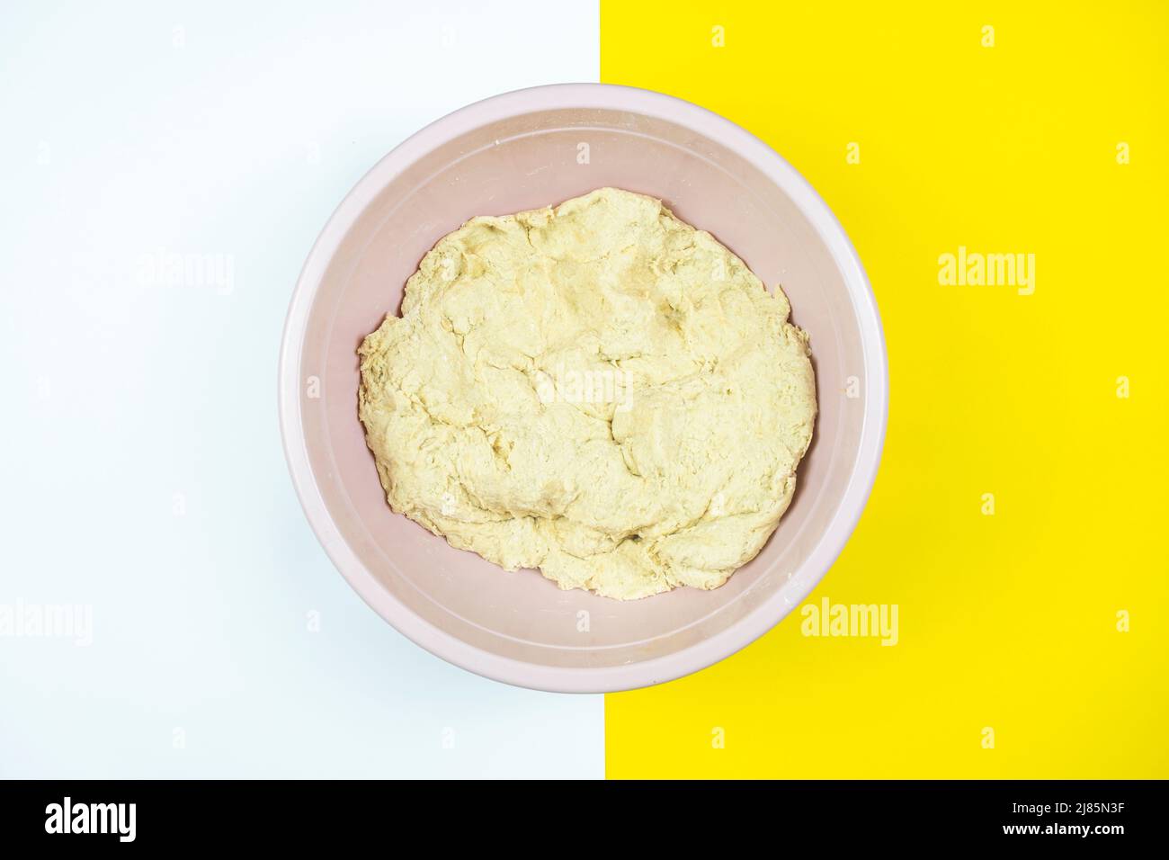 Knetteig in Kunststoffkoffer, Brotkonzept, Draufsicht, isoliert auf weißem und gelbem Hintergrund, Gebäck für Brot mit Kopierplatz Stockfoto