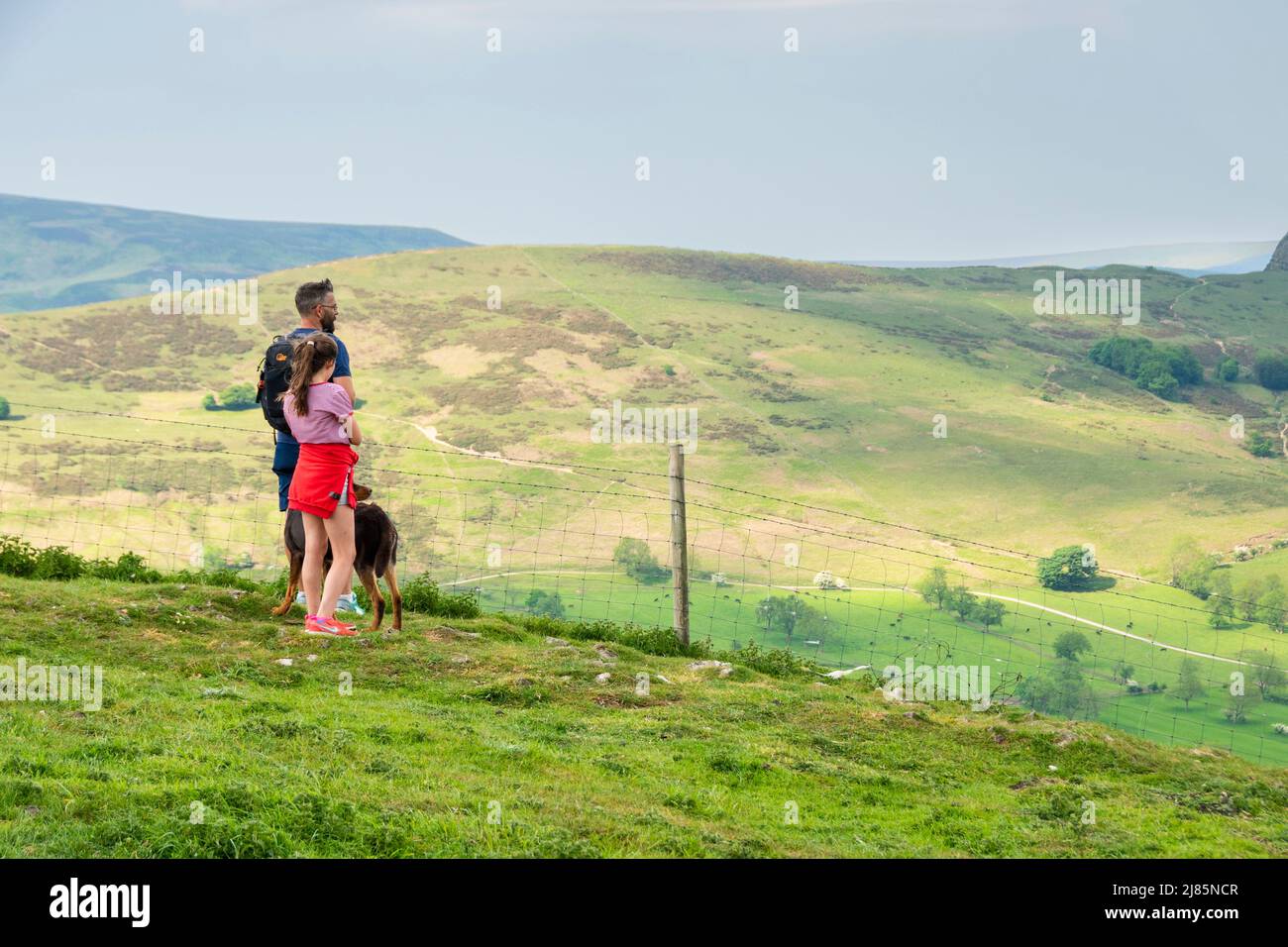 Derbyshire, Großbritannien – 5. April 2018: Ein Vater und eine Tochter ruhen sich auf ihrem Spaziergang aus, um den Blick auf die Moorlandschaft des Peak District vom Winnats Pass aus zu bewundern Stockfoto