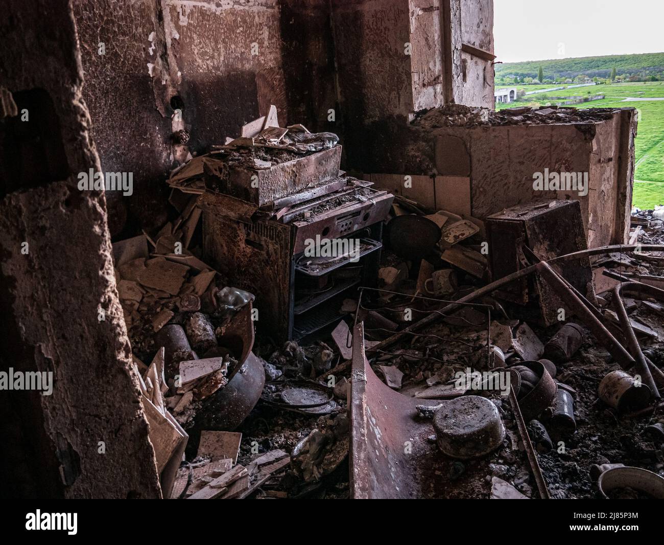 Charkiw, Charkow, Ukraine - 05.07.2022: Blick aus dem zerstörten Wohnküche gebrochener Ofen nach Raketenangriff zersplittert Metallziegel zerbrochener Wal Stockfoto