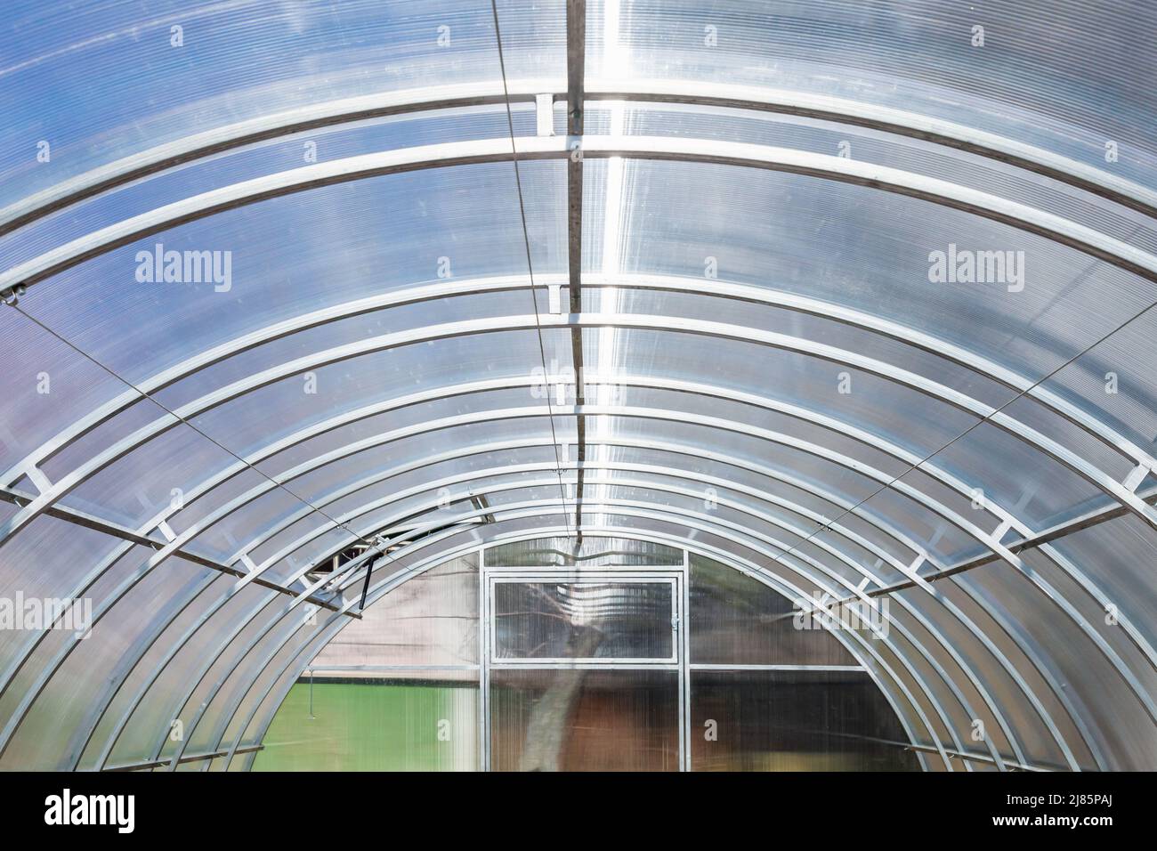 Modernes Gewächshaus im Innenbereich. Polycarbonat-Dach auf doppeltem gewölbtem Stahlrahmen montiert Stockfoto