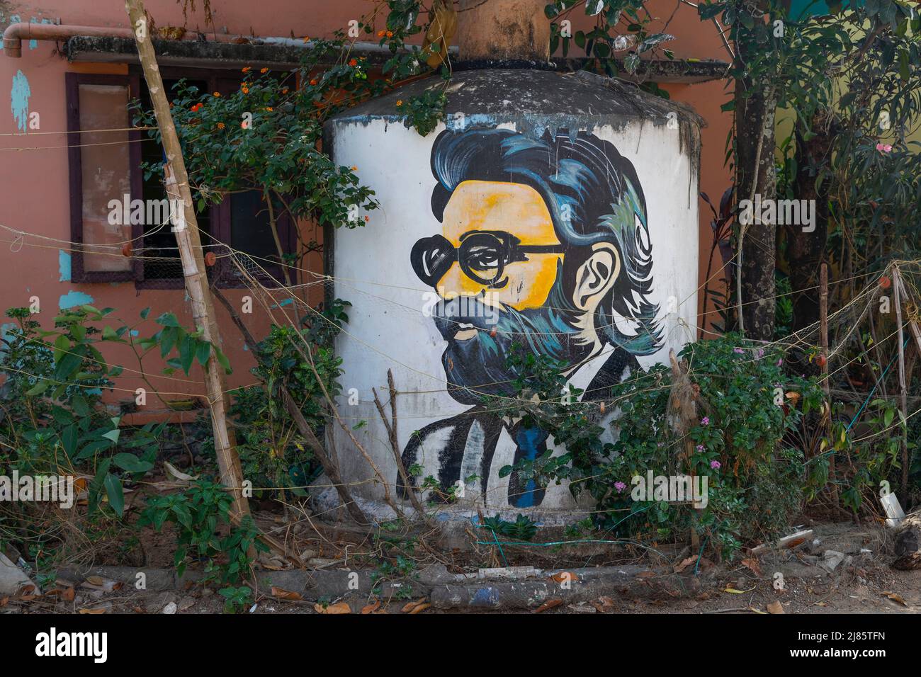 Abwassertank hinter einem Haus mit einem männlichen Graffiti-Porträt bedeckt, Tangassery, Thangassery, Kerala, Indien. Stockfoto