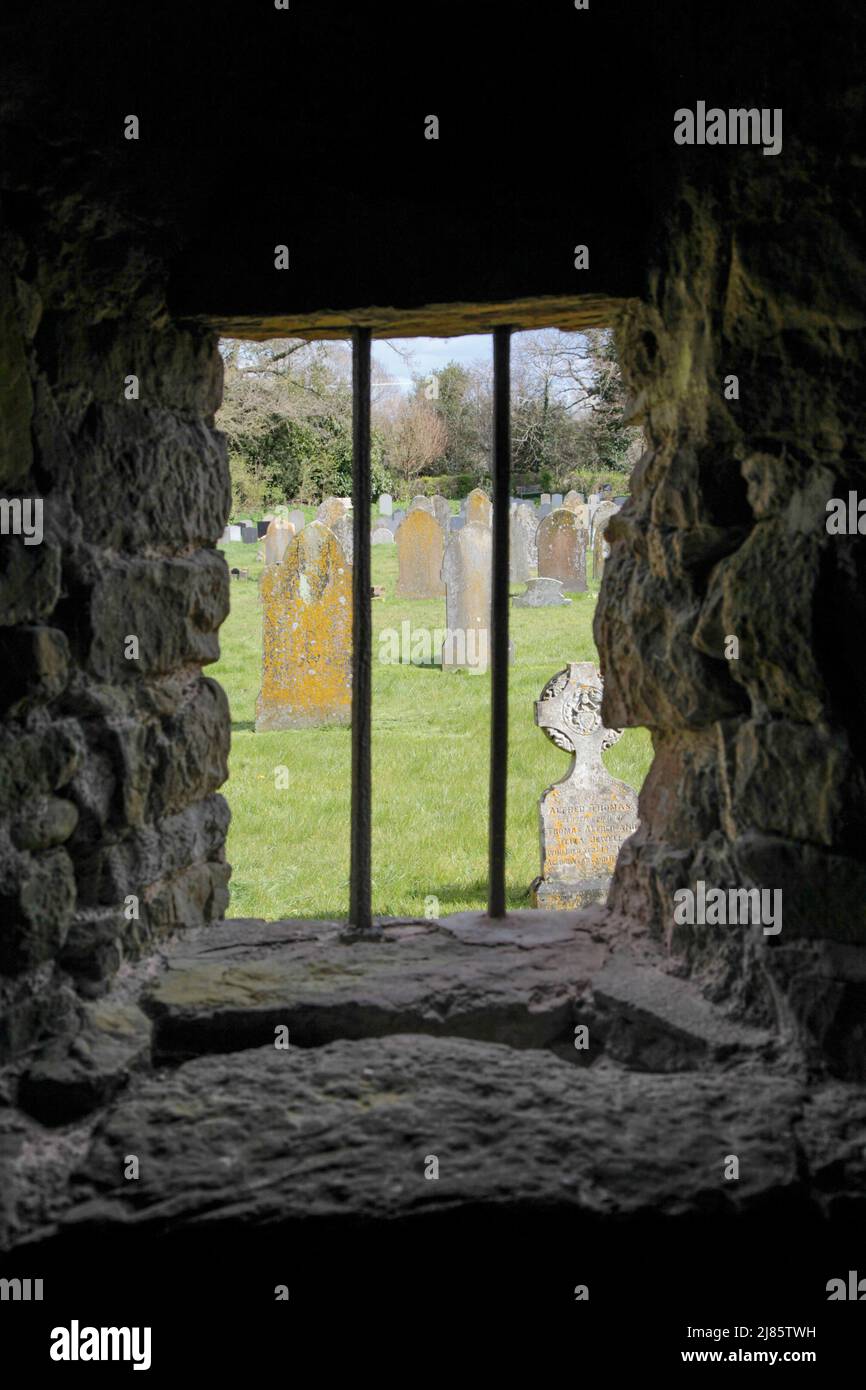 Blick auf den Friedhof, eingerahmt von einer Öffnung in einer dicken alten Steinmauer Stockfoto