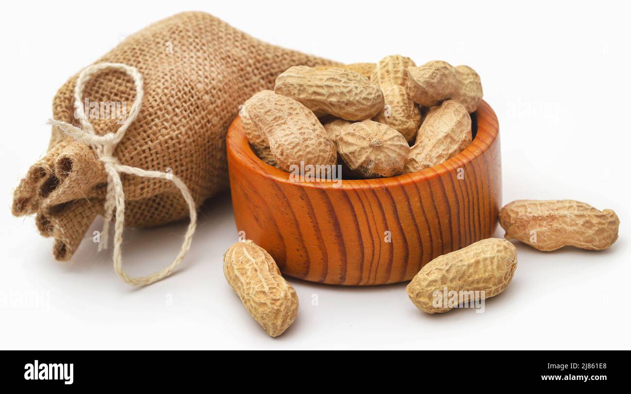Frische Erdnüsse in Sack und Schüssel auf weißem Hintergrund Stockfoto