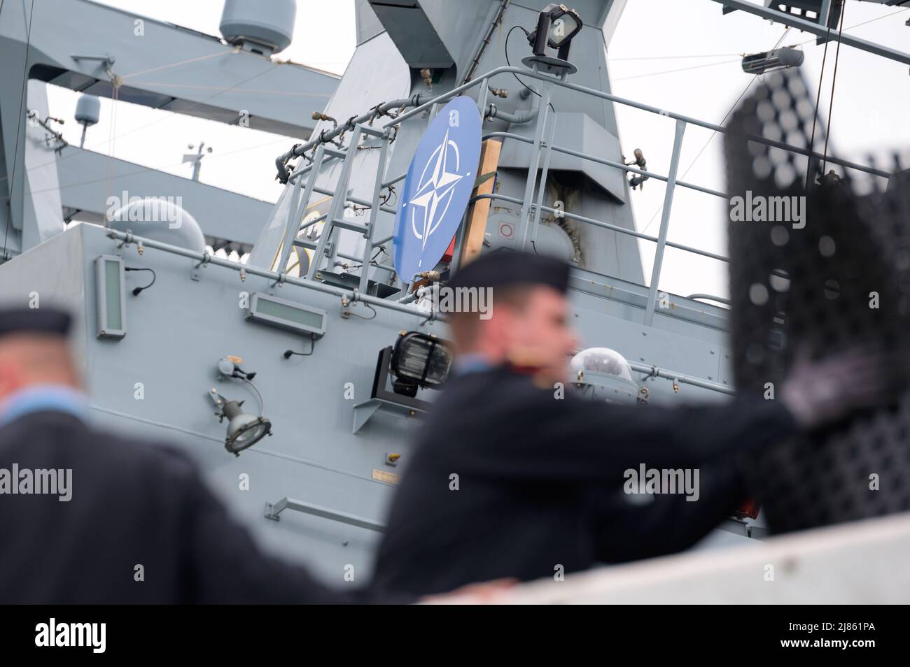 Hamburg, Deutschland. 13.. Mai 2022. Die Besatzung der deutschen Korvette 'Erfurt' lädt ihr Schiff vor ein Schild mit dem Symbol des NATO-Bündnisses. Die maritime Task Force der NATO besucht Hamburg, um die Vorräte aufzustocken. Zuvor waren sie in der Ostsee, um ein Signal der Verteidigungsbereitschaft zu senden, so die Bundeswehr. Quelle: Jonas Walzberg/dpa/Alamy Live News Stockfoto