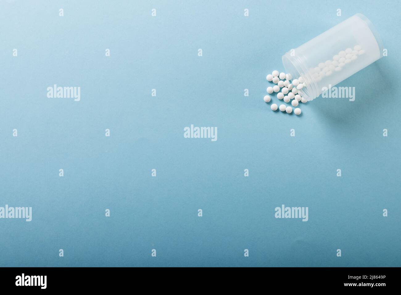 Direkt über Aufnahme von weißen Medikamenten, die aus der Flasche auf blauem Hintergrund verschüttet wurden, Platz kopieren Stockfoto