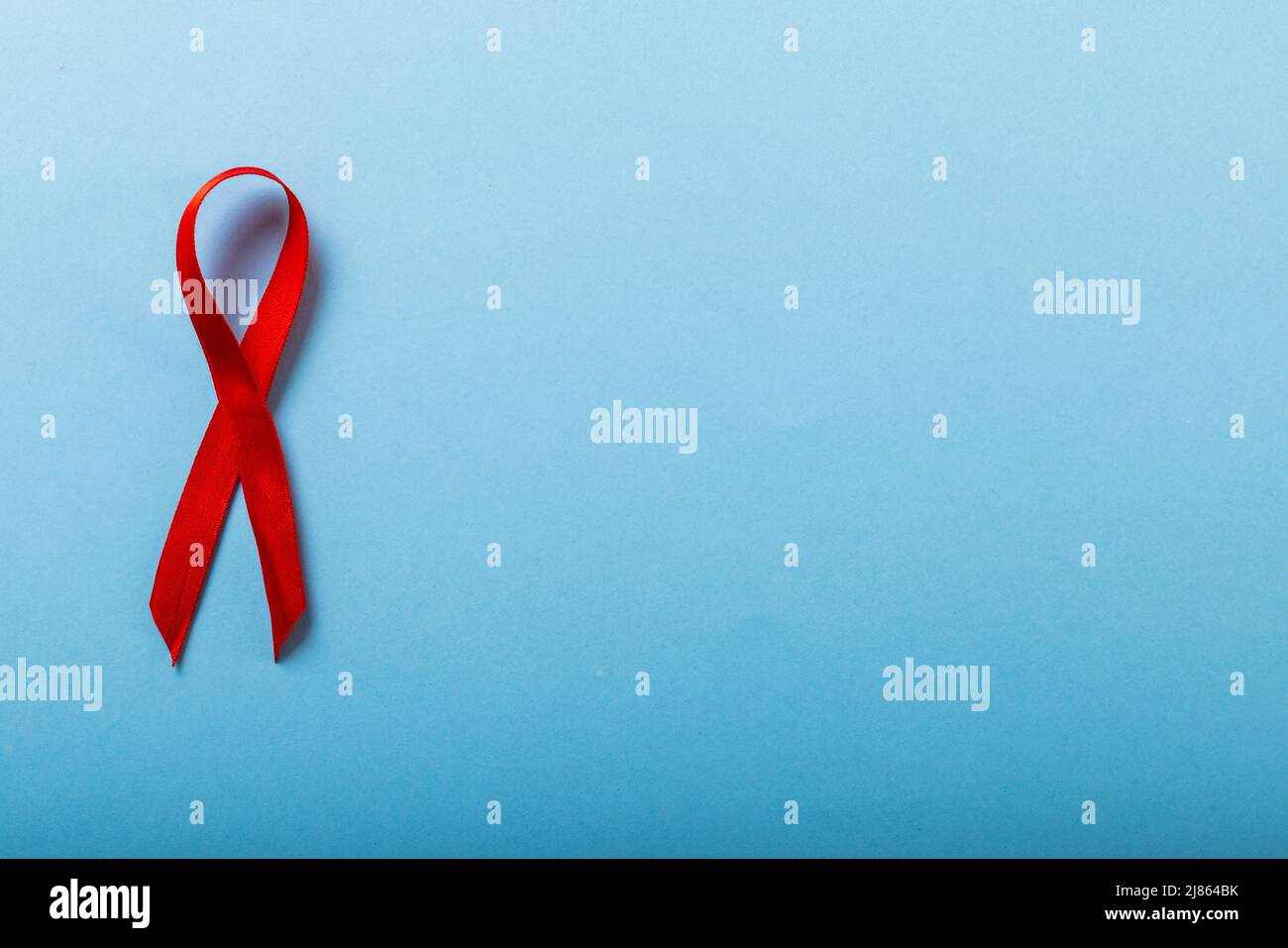 Direkt über der Aufnahme von Aids Awareness Ribbon rot isoliert vor blauem Hintergrund, Copy Space Stockfoto