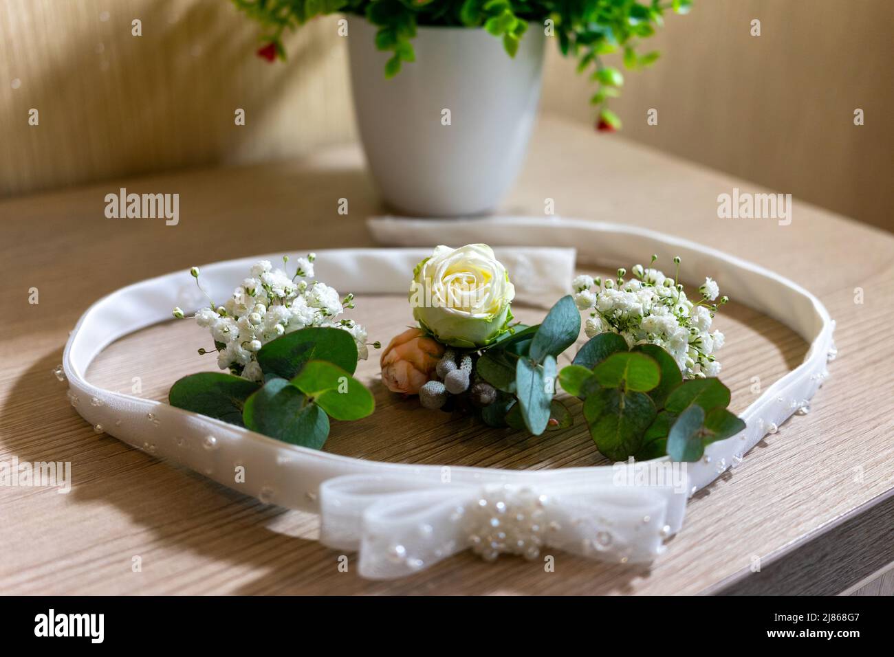Der Gürtel der Braut und die Hochzeitsboutonnieres liegen auf dem Tisch. Stockfoto