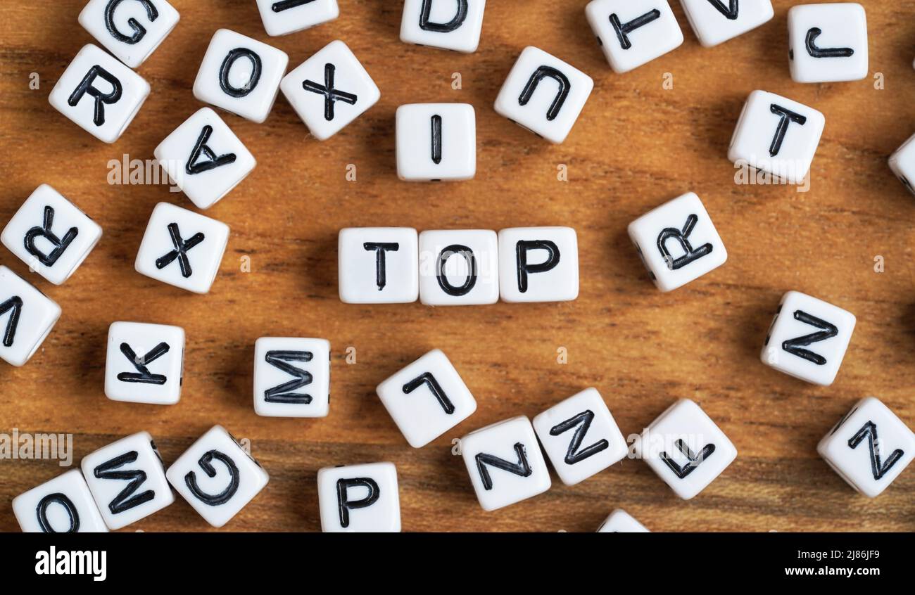Kleine weiße und schwarze Perlenwürfel auf Holzbrett, Buchstaben in der Mitte buchstabieren OBEN Stockfoto