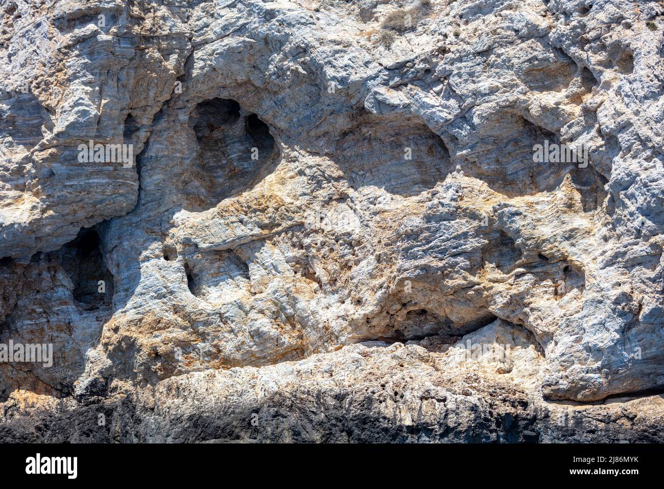 Grauer Fels, geformt vom Meer, Salz und Wind Hintergrundstruktur. Steinbildung, raues mineralisches Material. Abstrakte natürliche Felsoberfläche. Griechische Insel G Stockfoto