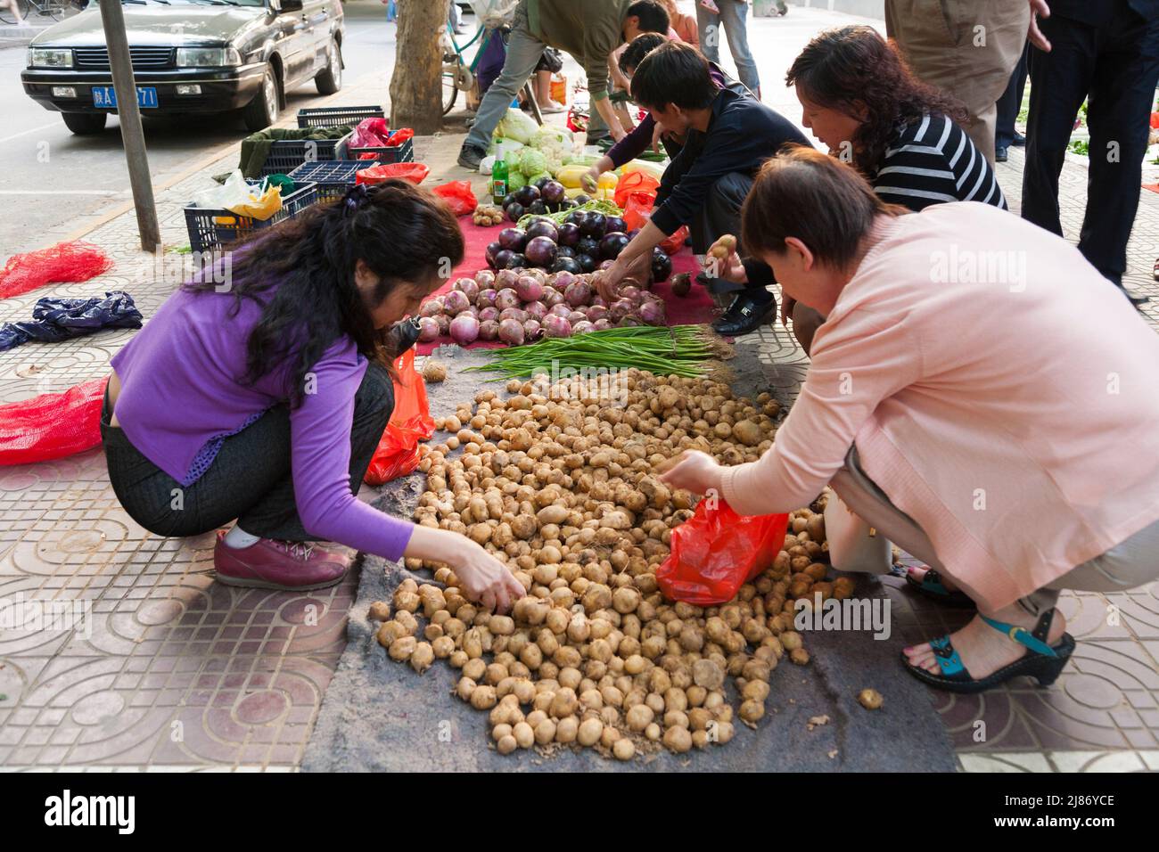 Bürgersteig Marktstand mit Obst und Gemüse auf dem Boden und Kunden auf der Suche nach Produkten zu kaufen. Stadt Xi'an in China VRC. (125) Stockfoto