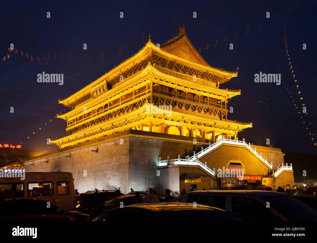 Trommelturm von Xi'an in der Nacht; außen vor dem historischen chinesischen Gebäude, das die Trommel beherbergt, die in der alten Stadt das Ende des Tages Klang. China. Drachen fliegen an einem warmen Abend am Himmel. (125) Stockfoto