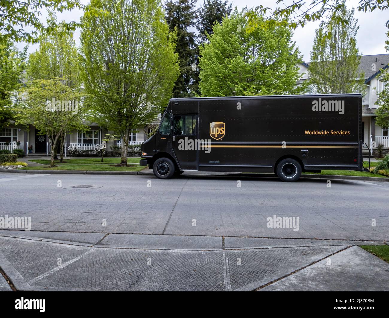 Mill Creek, WA USA - ca. Mai 2022: Vorderansicht eines braunen UPS-Lieferwagens außerhalb eines Wohnhauses, der eine Lieferung vornimmt. Stockfoto