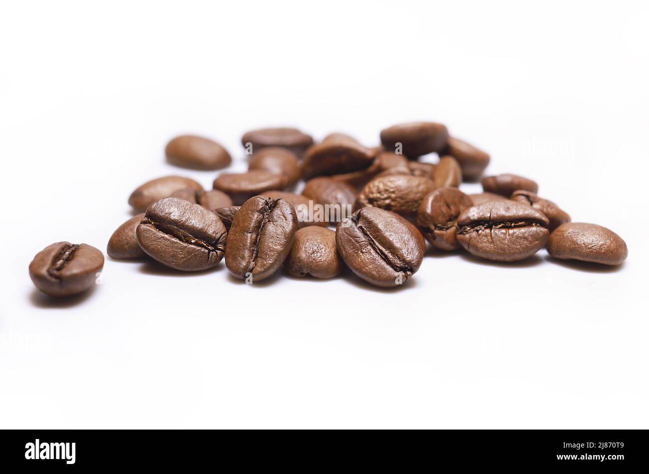 Stapel von Bohnen mit mittelbraöstlichem Kaffee auf weißem Hintergrund. Geröstete Arabica-Kaffeebohnen. Geröstete Kaffeebohnen auf weißem Hintergrund. Koffeinaroma Stockfoto