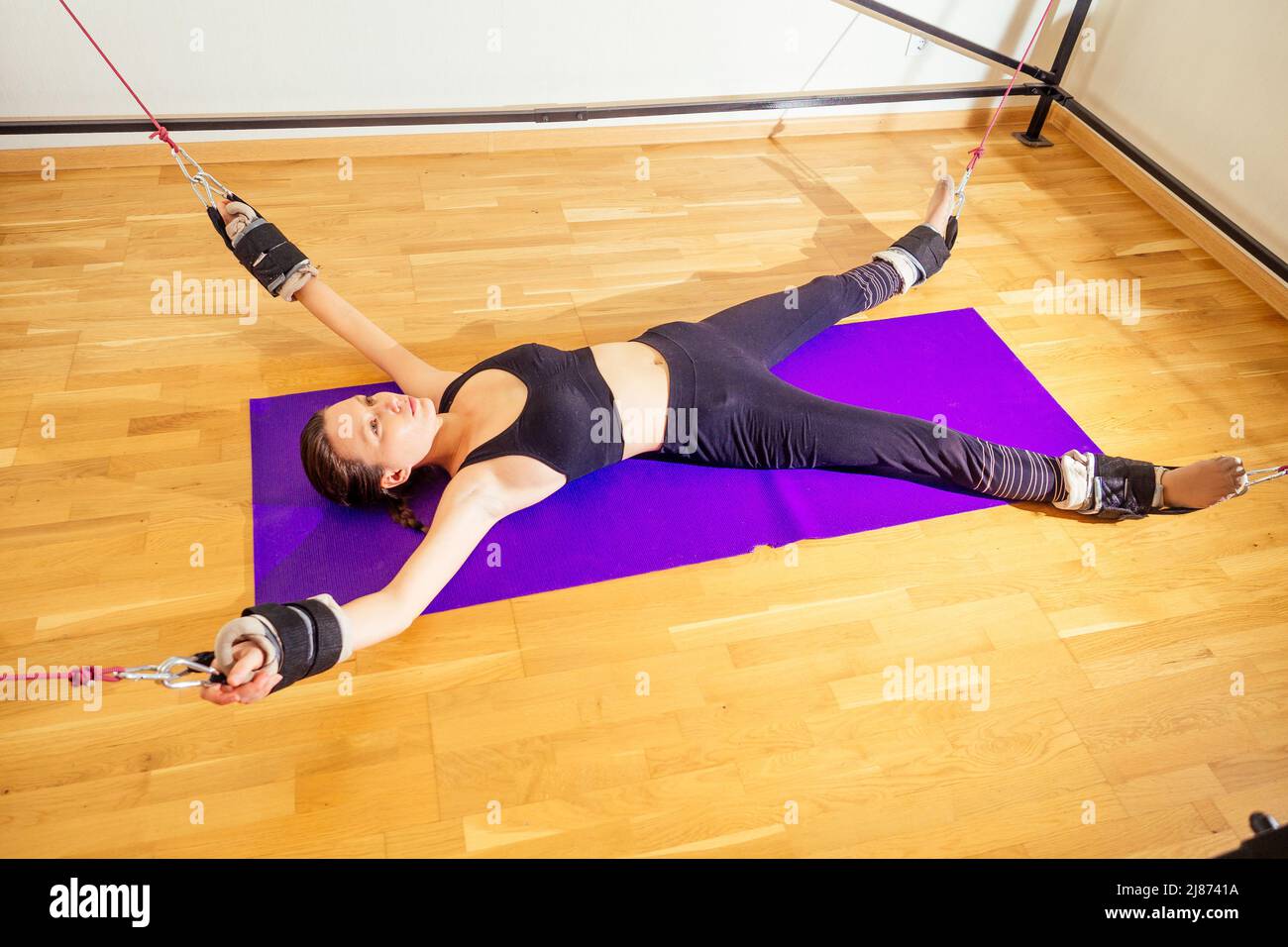 Sportliche junge kaukasische Frau macht Stretching-Übungen der Ganzkörpermuskulatur Training auf Stretch Aerobic Aero Gurt in der Turnhalle, Yogi Matte Stockfoto