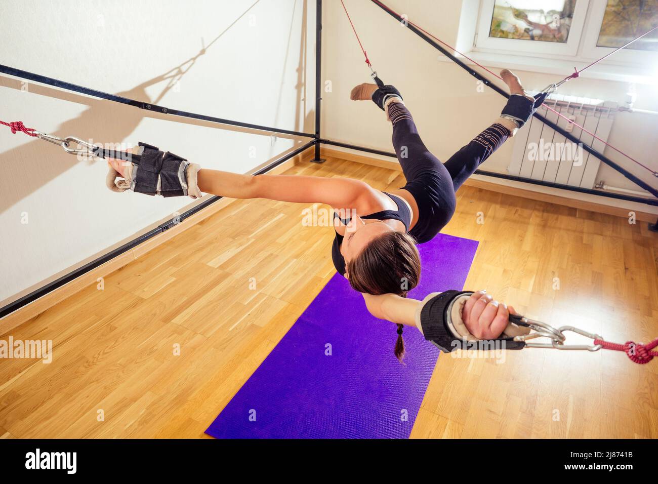 Sportliche junge kaukasische Frau macht Stretching-Übungen der Ganzkörpermuskulatur Training auf Stretch Aerobic Aero Gurt in der Turnhalle, Yogi Matte Stockfoto