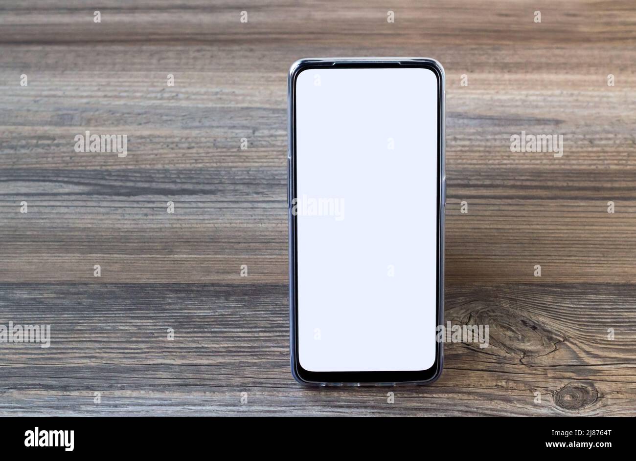Smartphone mit weißem leeren Bildschirm, der auf einer Holzoberfläche mit Kopierfläche steht, Stockfoto