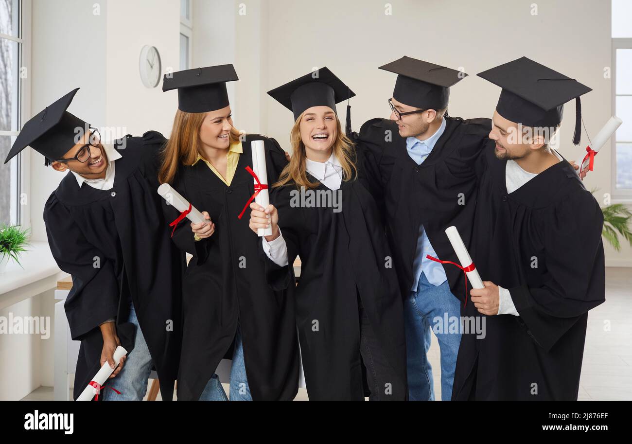 Eine vielfältige Gruppe von glücklichen Universitätsfreunden umarmte sich und hatte Spaß an ihrem Abschluss Stockfoto