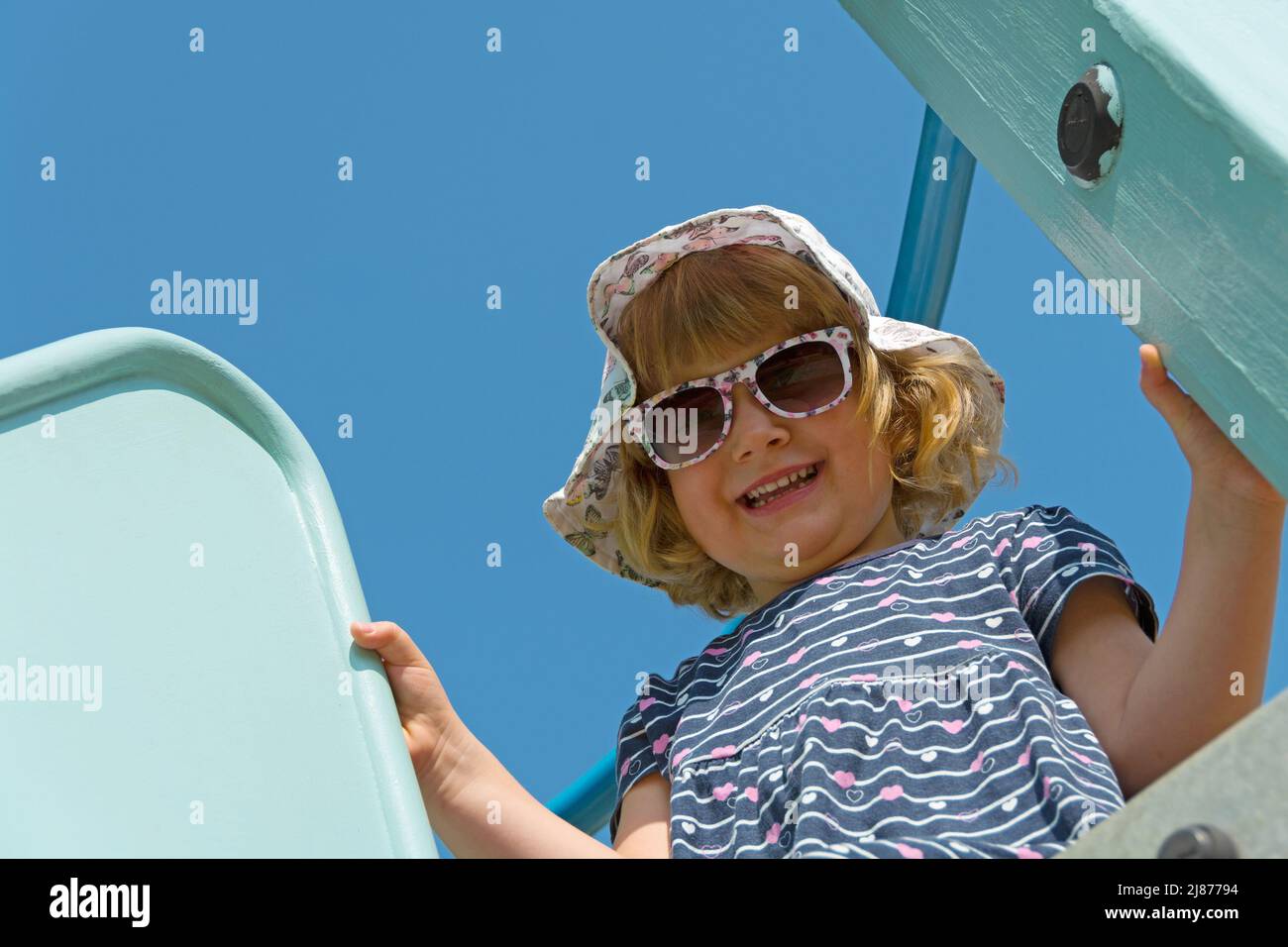 Das Kind schaut lachend vom Klettergerüst herunter Stockfoto
