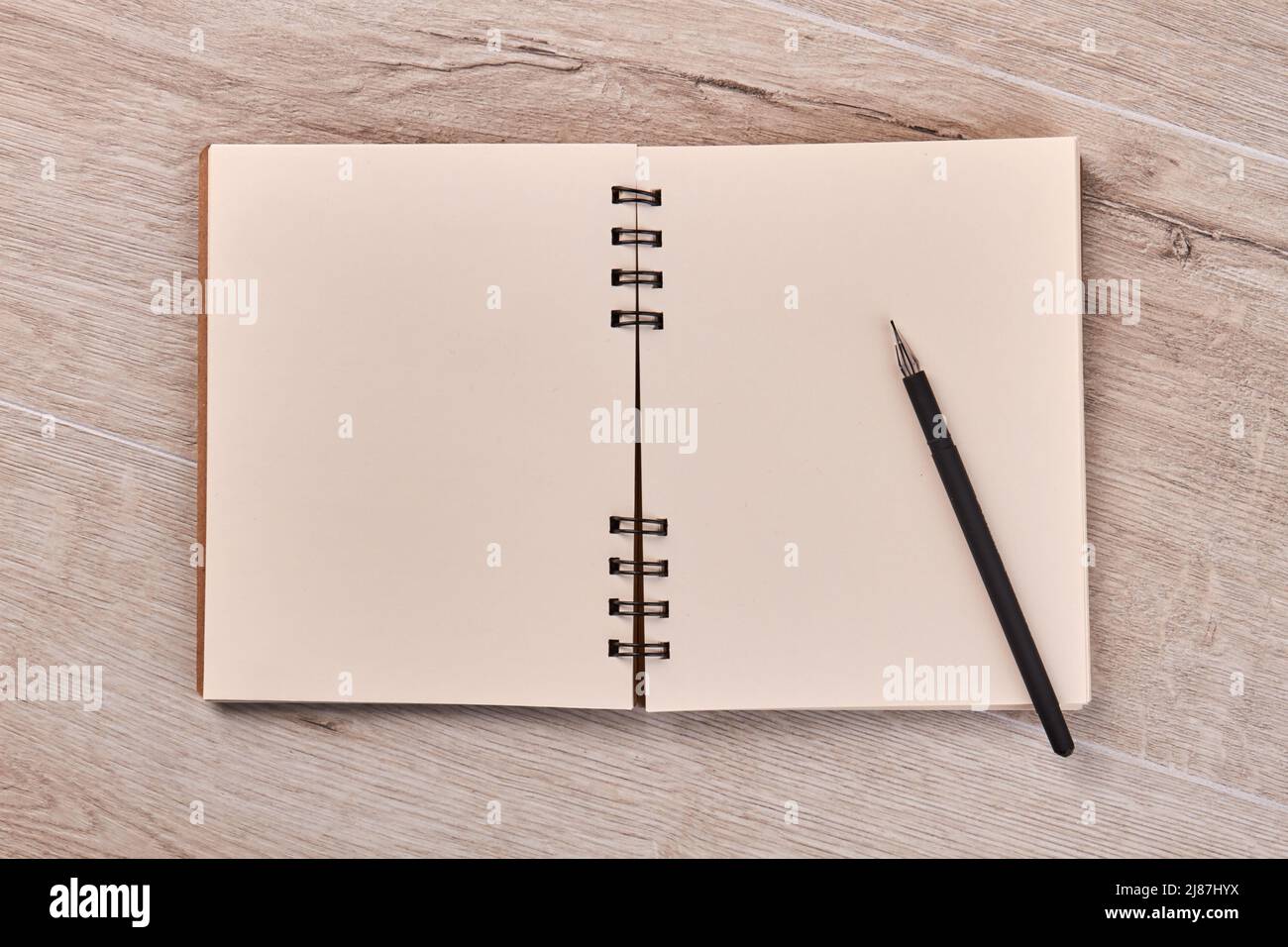 Leerer Notizblock mit Stift auf Holzschreibtisch. Draufsicht flach liegend. Stockfoto