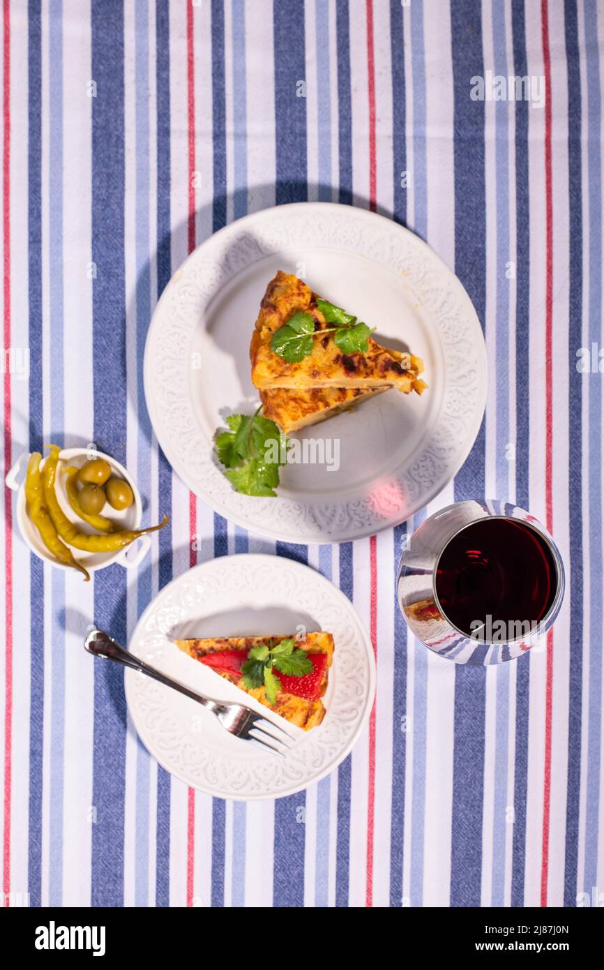 Traditionelle spanische Tortilla-Patatas mit rotem Piquillo-Pfeffer und einem Glas Wein. Stockfoto