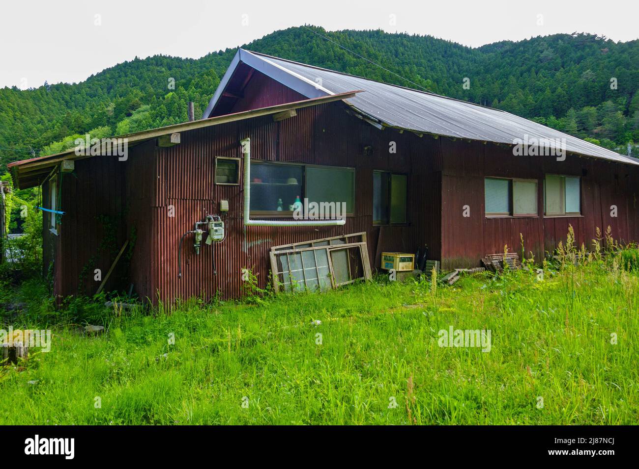 Verlassenes Haus aus Wellblech auf grünen Hügeln Stockfoto