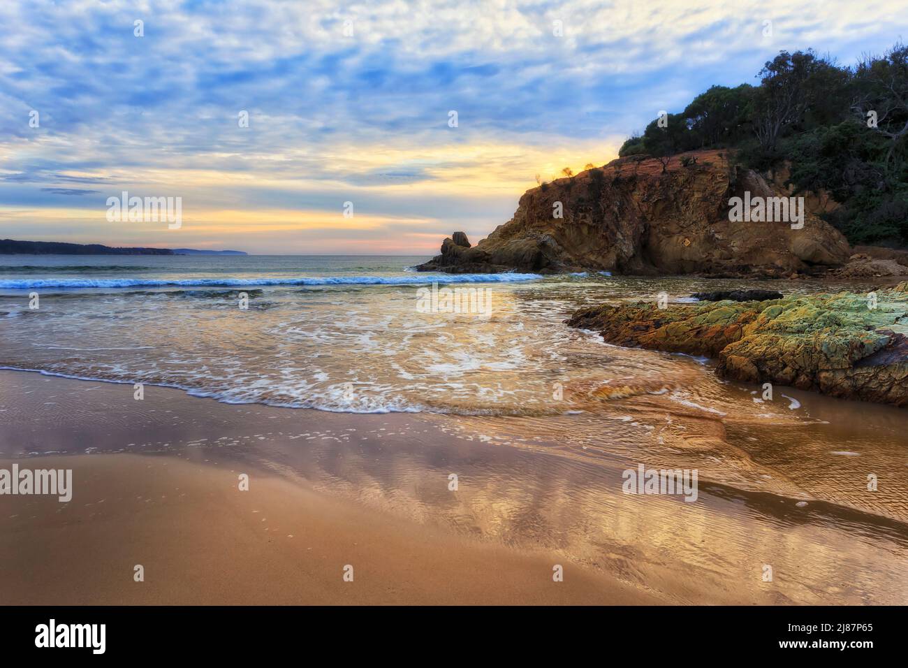 Sanftes Sonnenlicht auf dem Sand des Tathra Beach an der australischen Sapphire Coast - malerische Meereslandschaft. Stockfoto